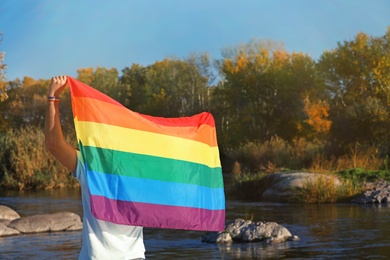 Photo of Man with rainbow LGBT flag outdoors, space for text. Gay symbol