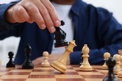 Photo of Man moving knight on chessboard indoors, closeup