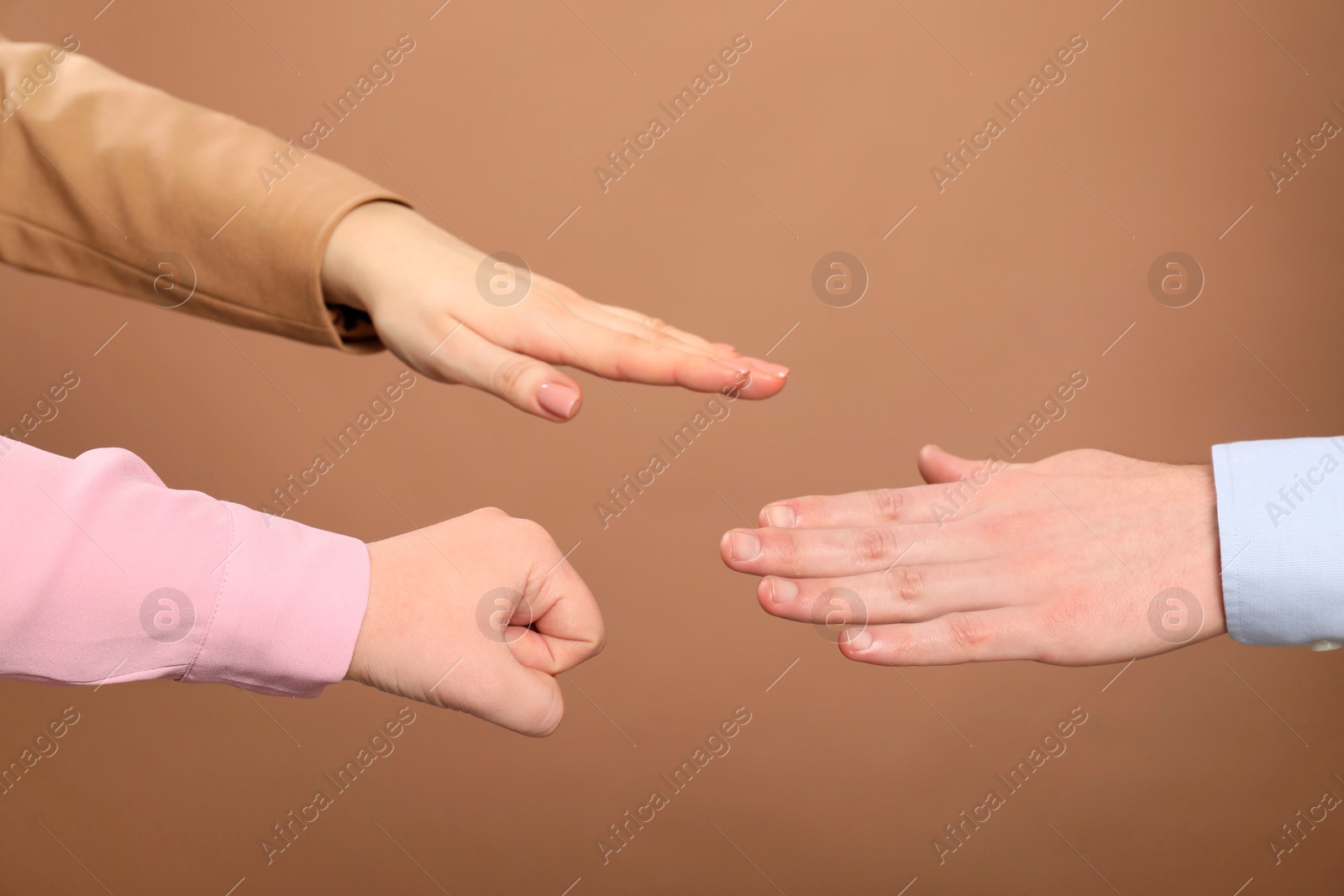 Photo of People playing rock, paper and scissors on brown background, closeup