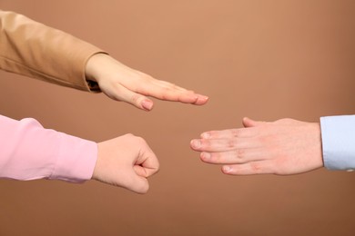 People playing rock, paper and scissors on brown background, closeup