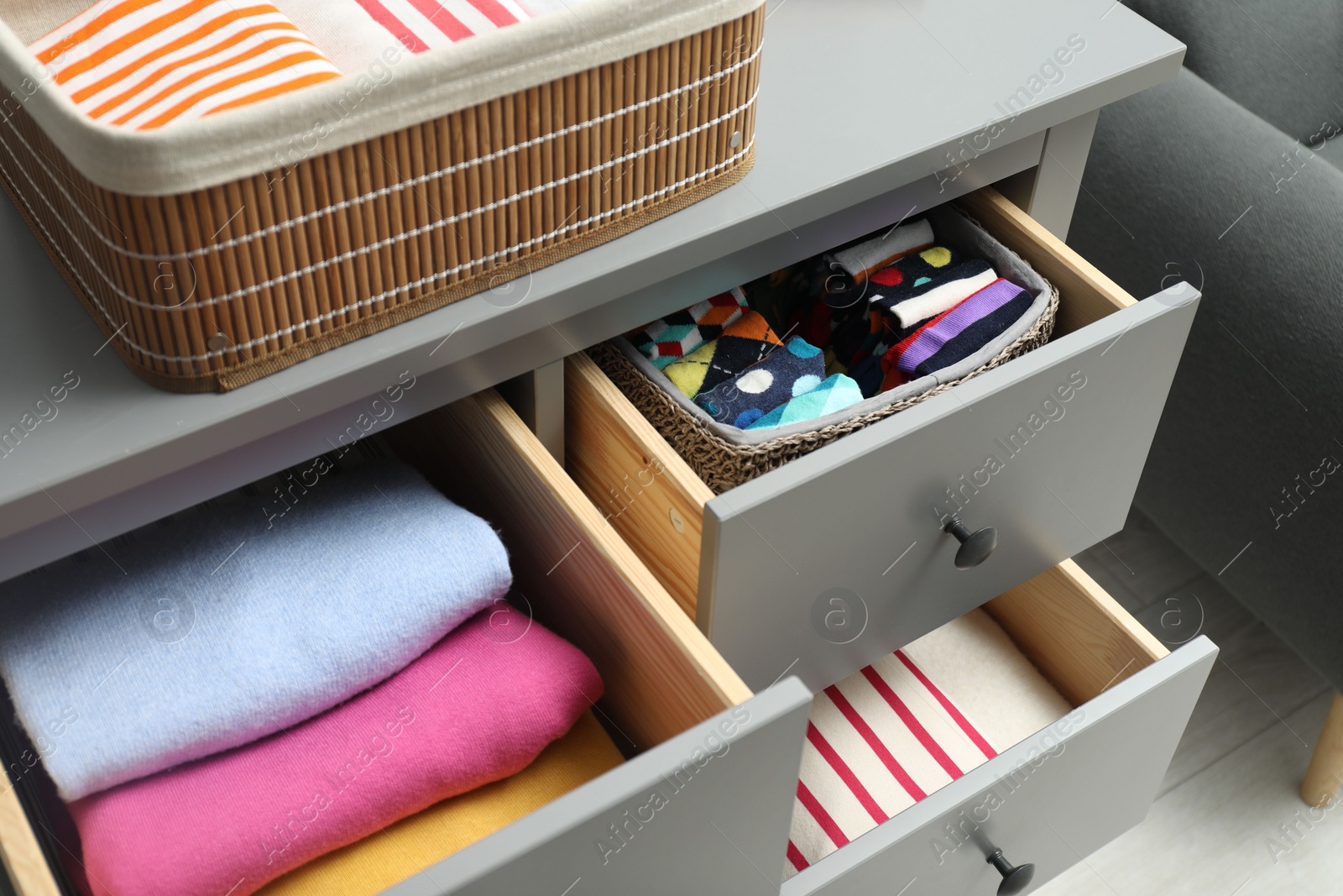 Photo of Chest of drawers with different folded clothes indoors, above view