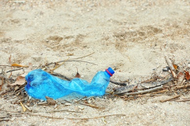 Photo of Used plastic bottle on beach, space for text. Recycling problem