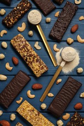 Photo of Different tasty bars, nuts and protein powder on blue wooden table, flat lay