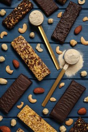 Different tasty bars, nuts and protein powder on blue wooden table, flat lay