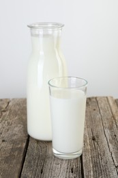 Photo of Carafe and glass of fresh milk on wooden table