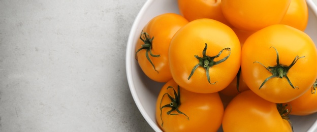 Photo of Ripe yellow tomatoes on grey table, top view. Space for text