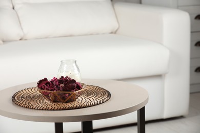 Aromatic potpourri of dried flowers in bowl and candle on white table indoors. Space for text