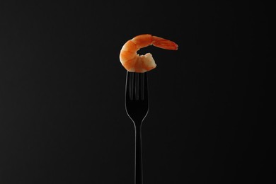 Fork with one shrimp on black background