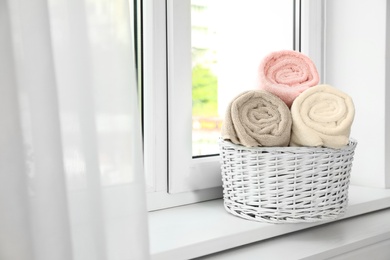 Basket with clean soft towels on window sill. Space for text