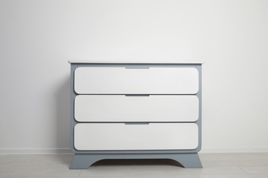 Photo of Modern wooden chest of drawers at light wall