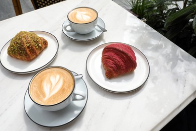 Photo of Delicious croissants and coffee on white marble table