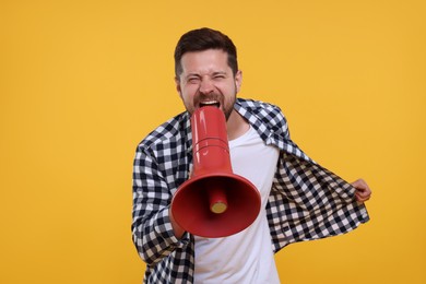 Photo of Emotional sports fan with megaphone on yellow background