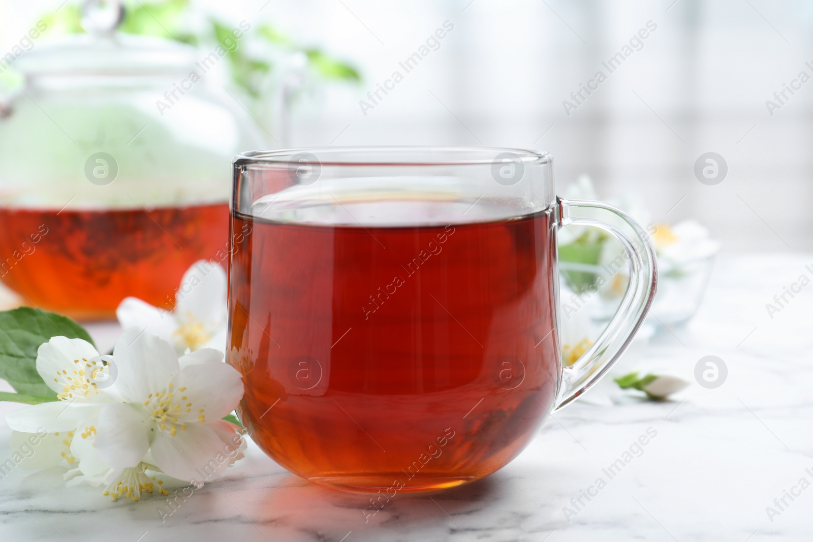 Photo of Cup of tea and fresh jasmine flowers on white marble table