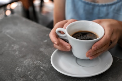 Photo of Woman with cup of fresh aromatic coffee at table, closeup
