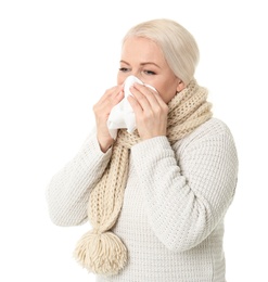 Mature woman with tissue suffering from cold on white background