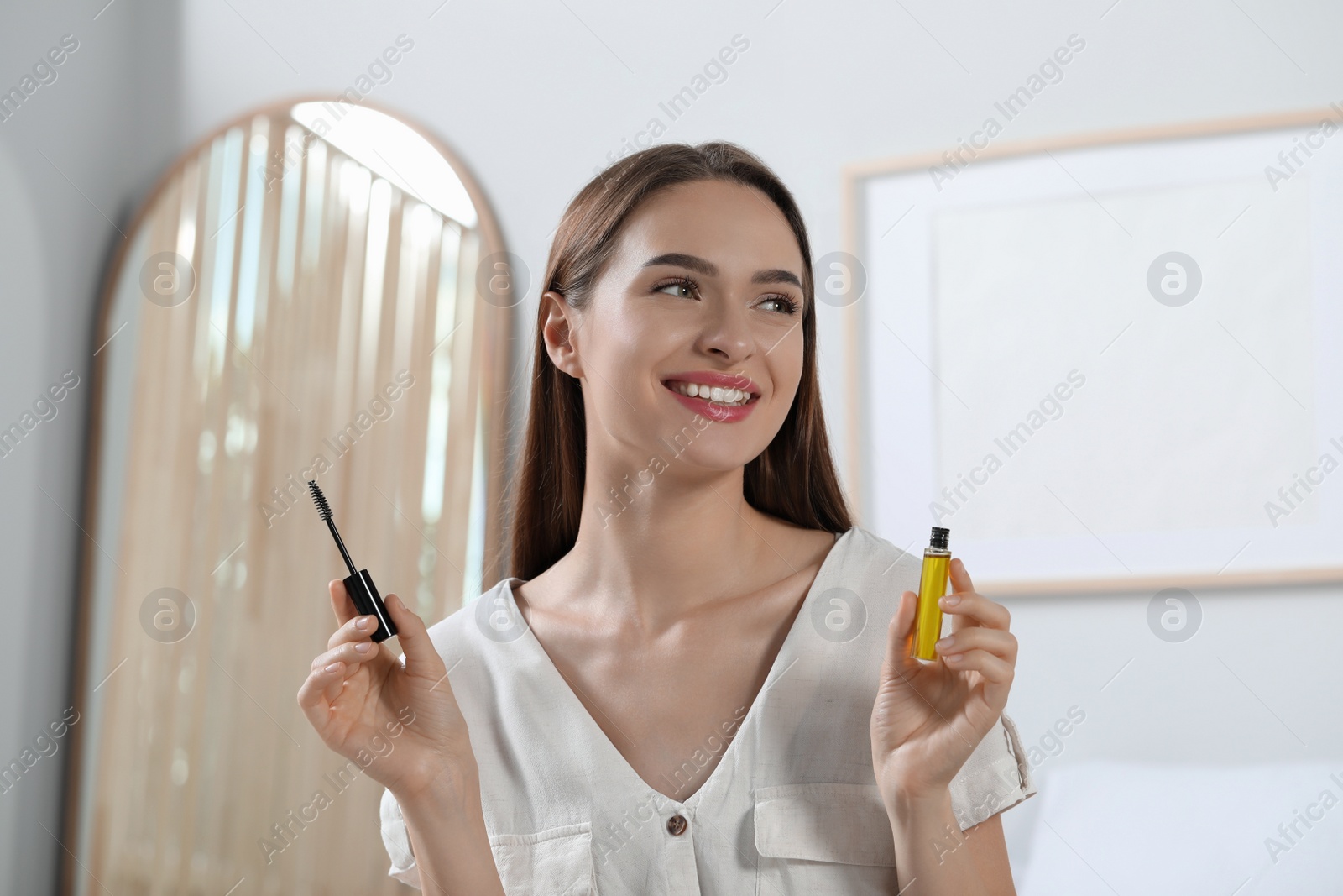 Photo of Young woman with eyelash oil at home