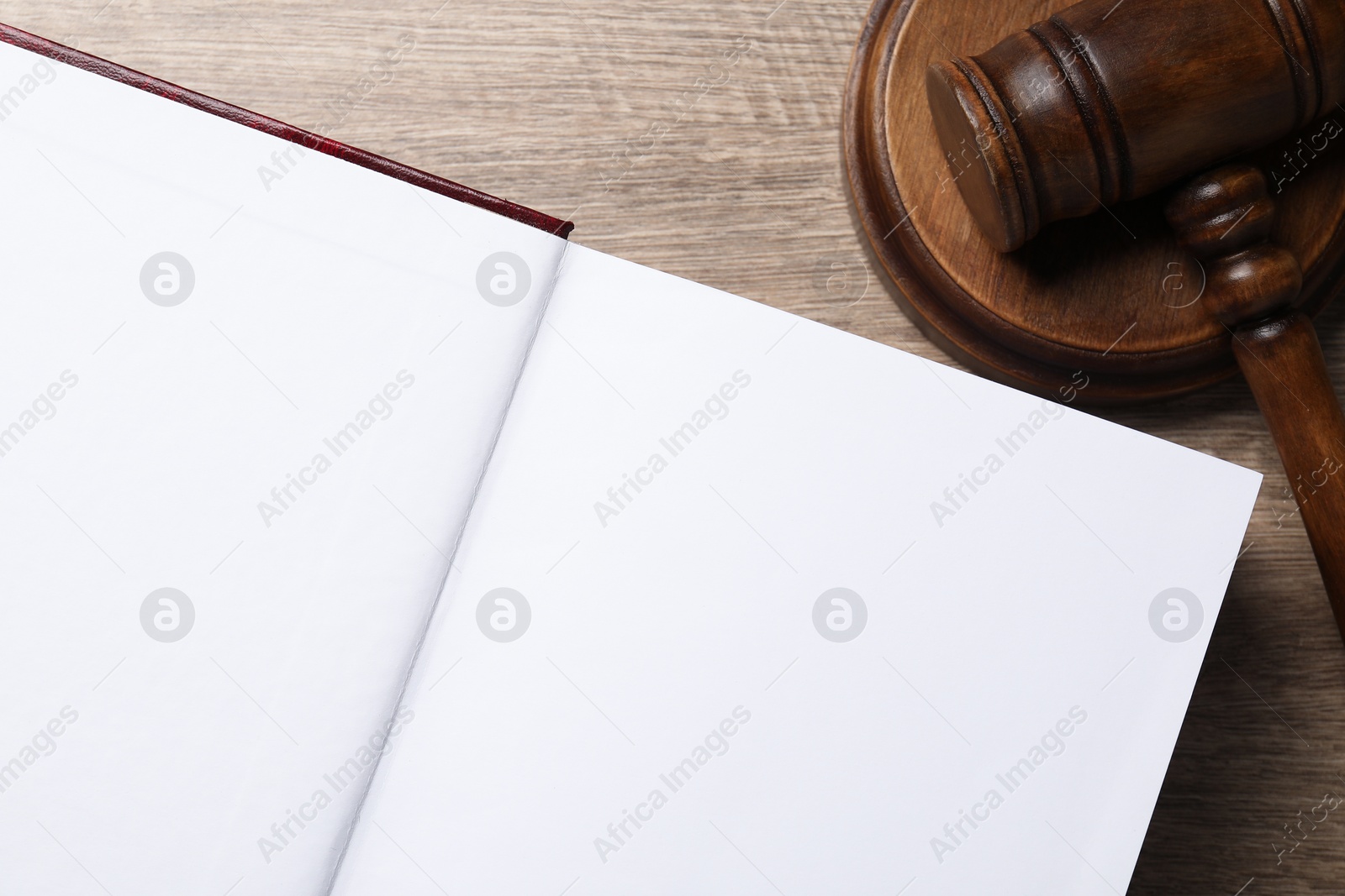 Photo of Law. Open book and gavel on wooden table, top view