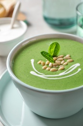 Cup of healthy green soup with fresh spinach on table, closeup