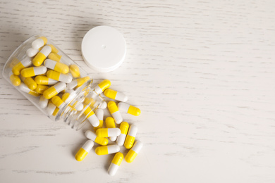 Bottle with vitamin pills on light table, flat lay. Space for text