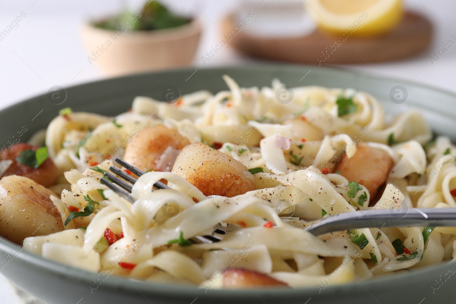 Photo of Delicious scallop pasta with spices in bowl served on table, closeup