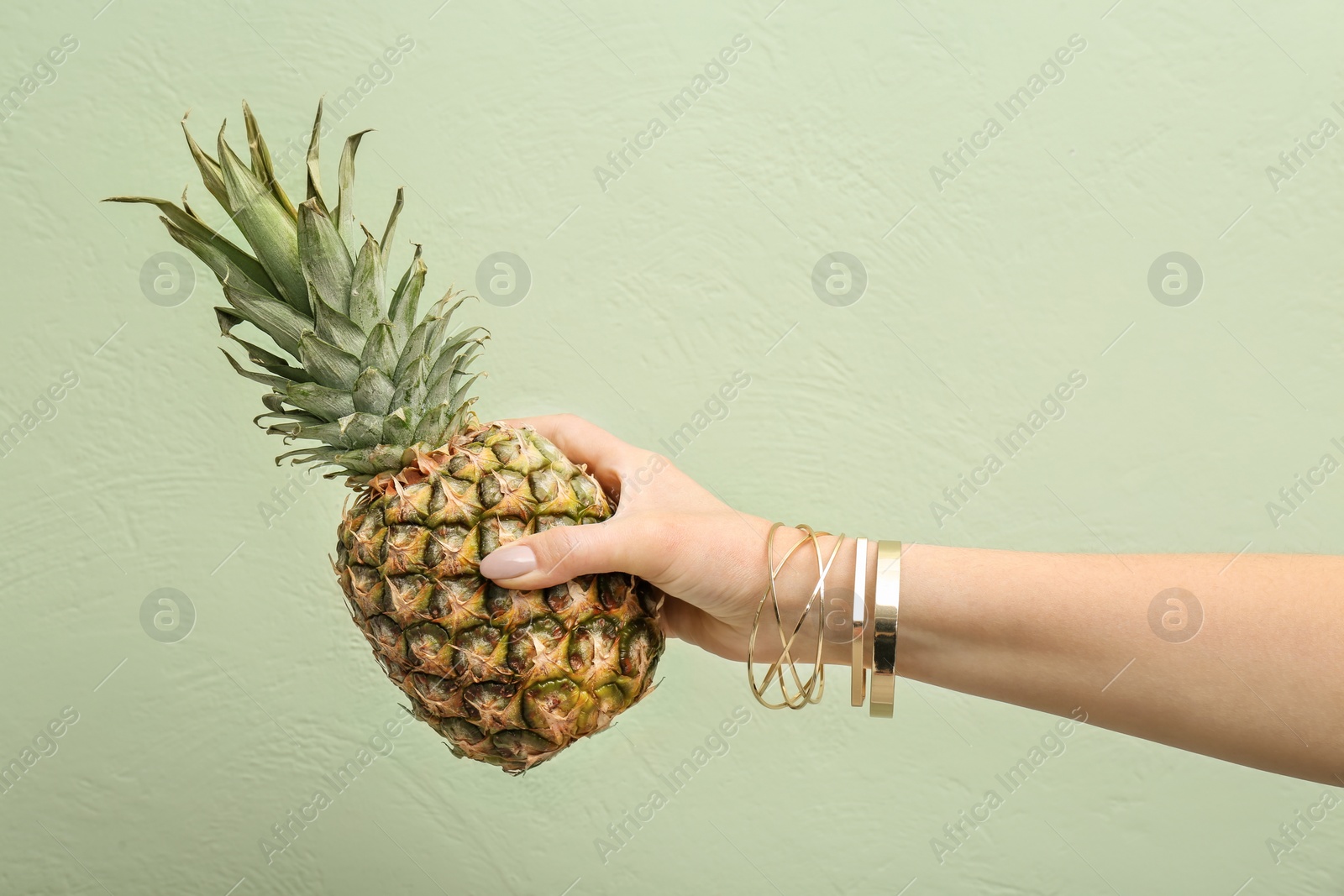 Photo of Woman holding pineapple on color background, closeup