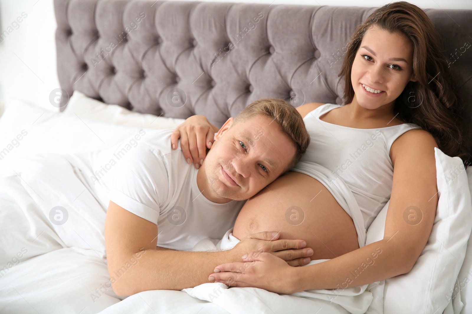Photo of Pregnant woman with her husband in bedroom. Happy young family