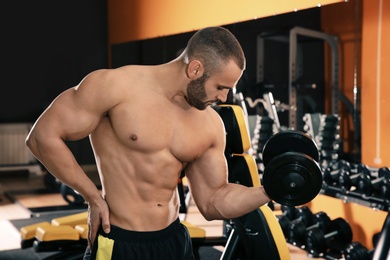 Photo of Strong young man lifting dumbbell in gym