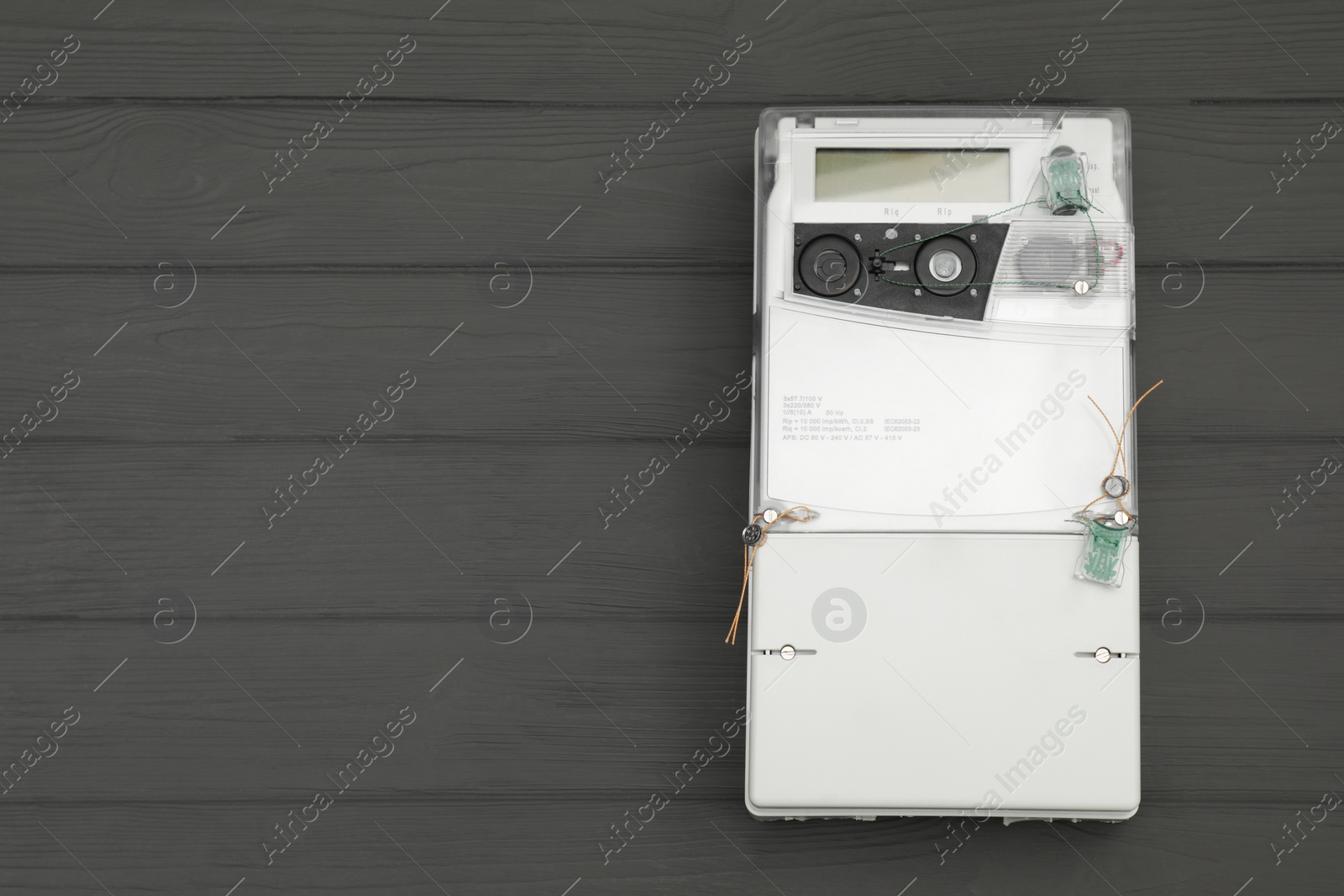 Photo of Electric meter on grey wooden background, top view with space for text. Measuring device