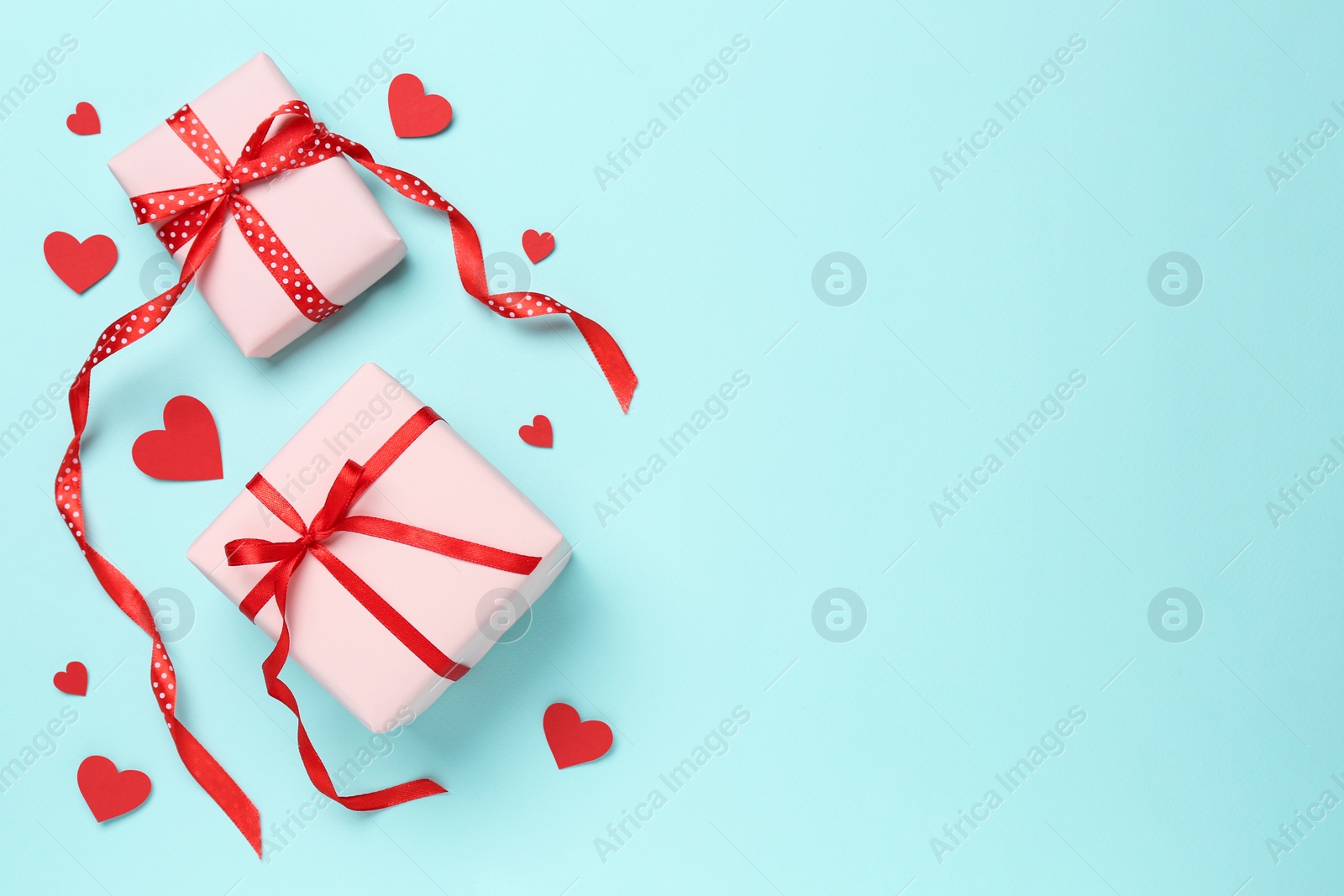 Photo of Gift boxes with decorative red hearts on turquoise background, flat lay. Space for text