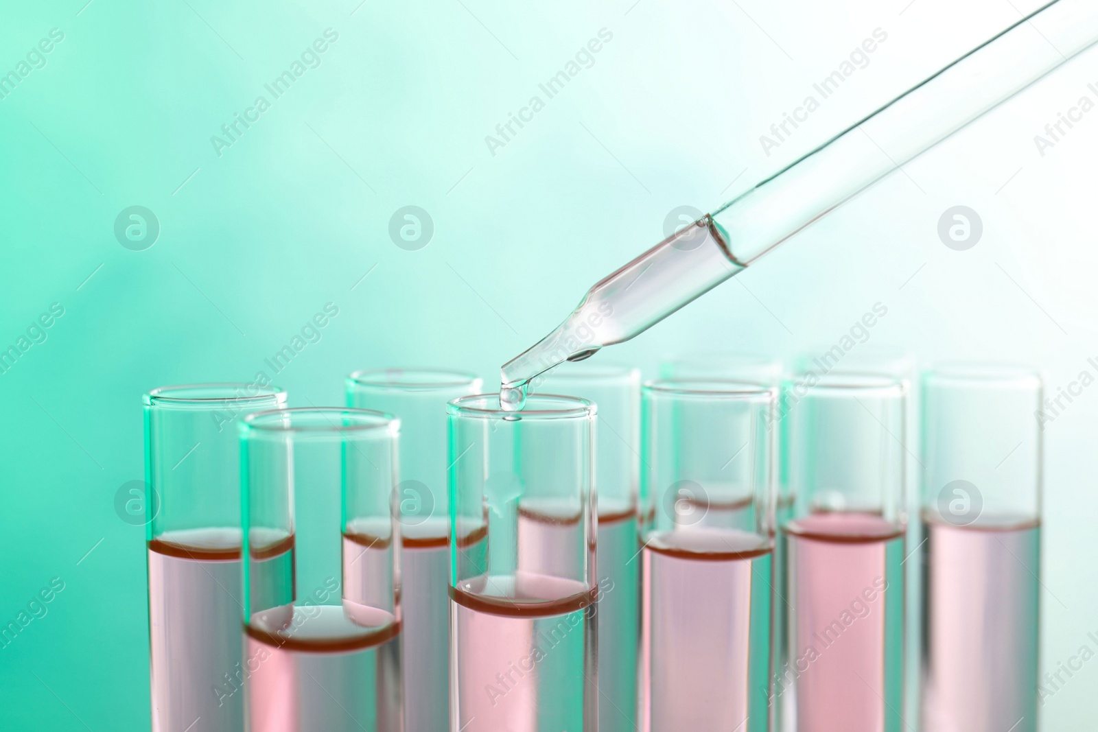 Photo of Dropping sample into test tube with liquid on color background, closeup