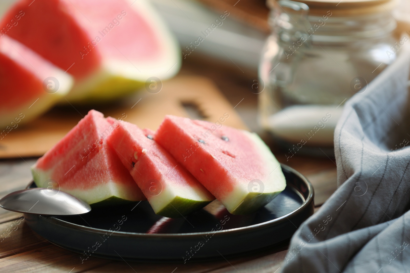 Photo of Sliced fresh juicy watermelon and spoon on wooden table, closeup