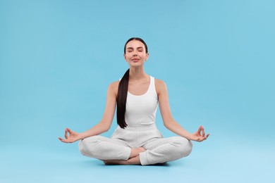 Photo of Beautiful young woman practicing yoga on light blue background. Lotus pose