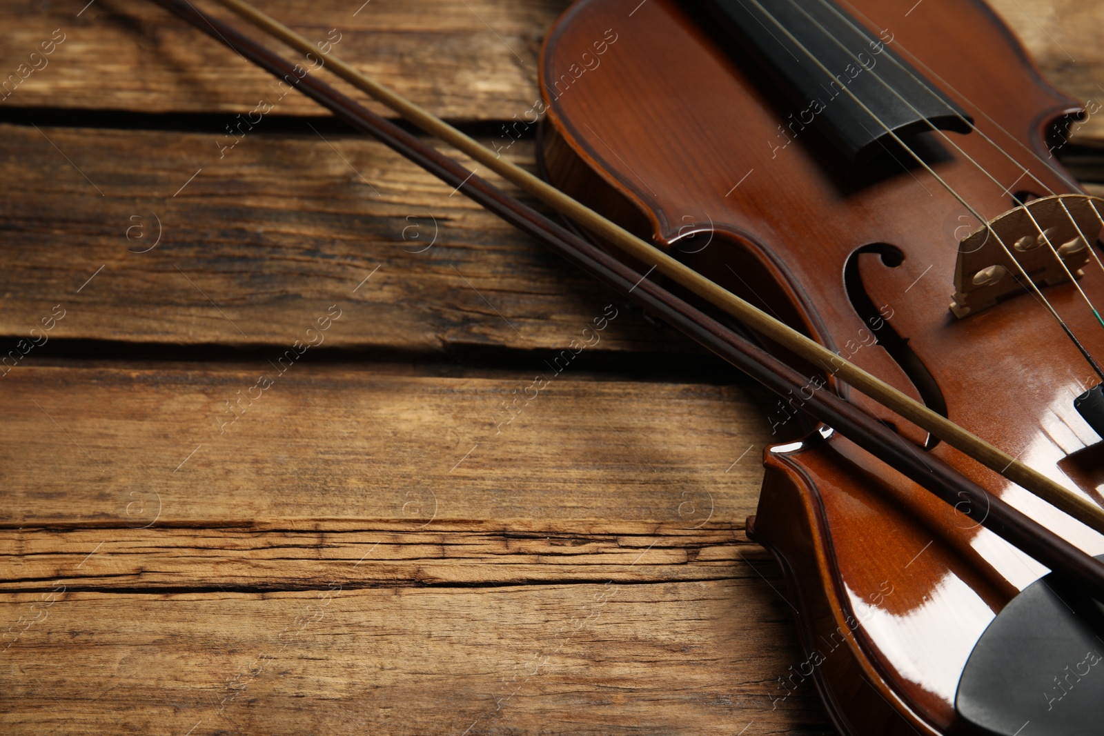Photo of Classic violin and bow on wooden background, closeup. Space for text