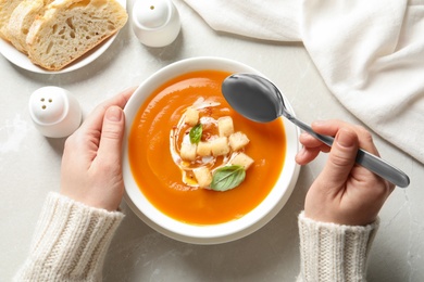Photo of Woman eating sweet potato soup at table, top view