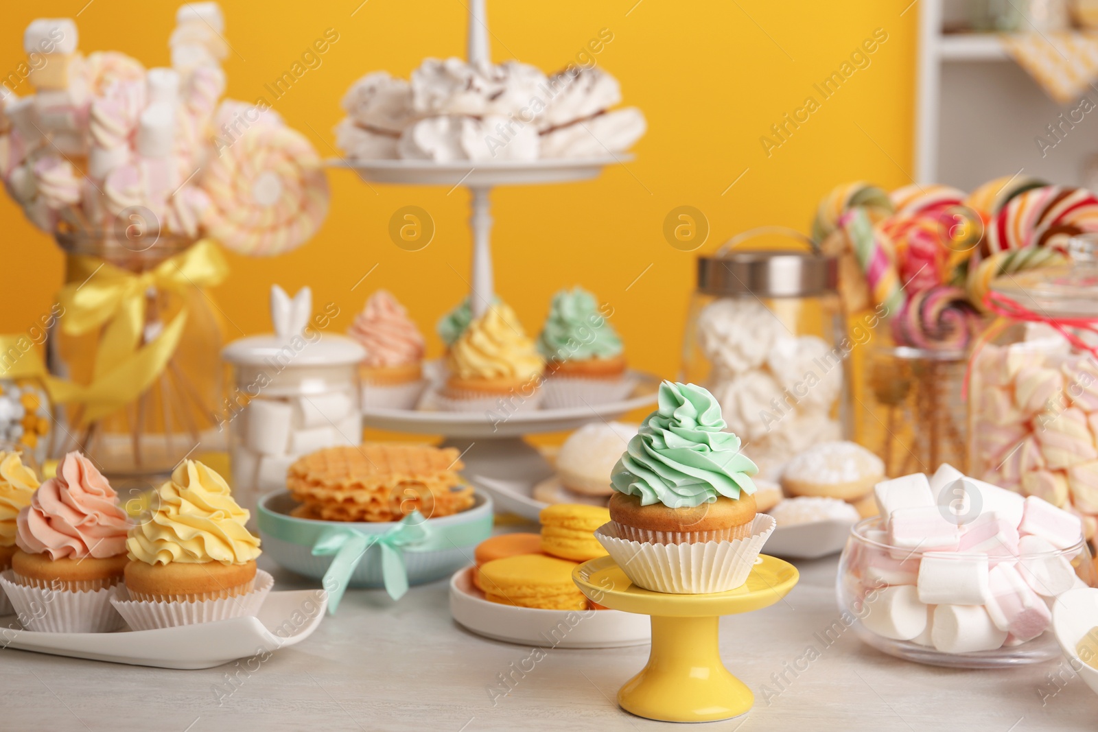 Photo of Tasty cupcakes and other sweets on table in room. Candy bar