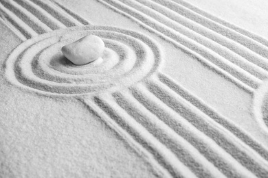 Photo of White stone on sand with pattern. Zen, meditation, harmony
