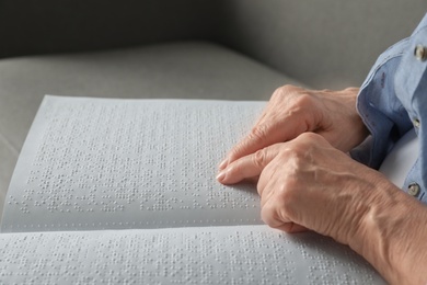 Blind senior person reading book written in Braille, closeup