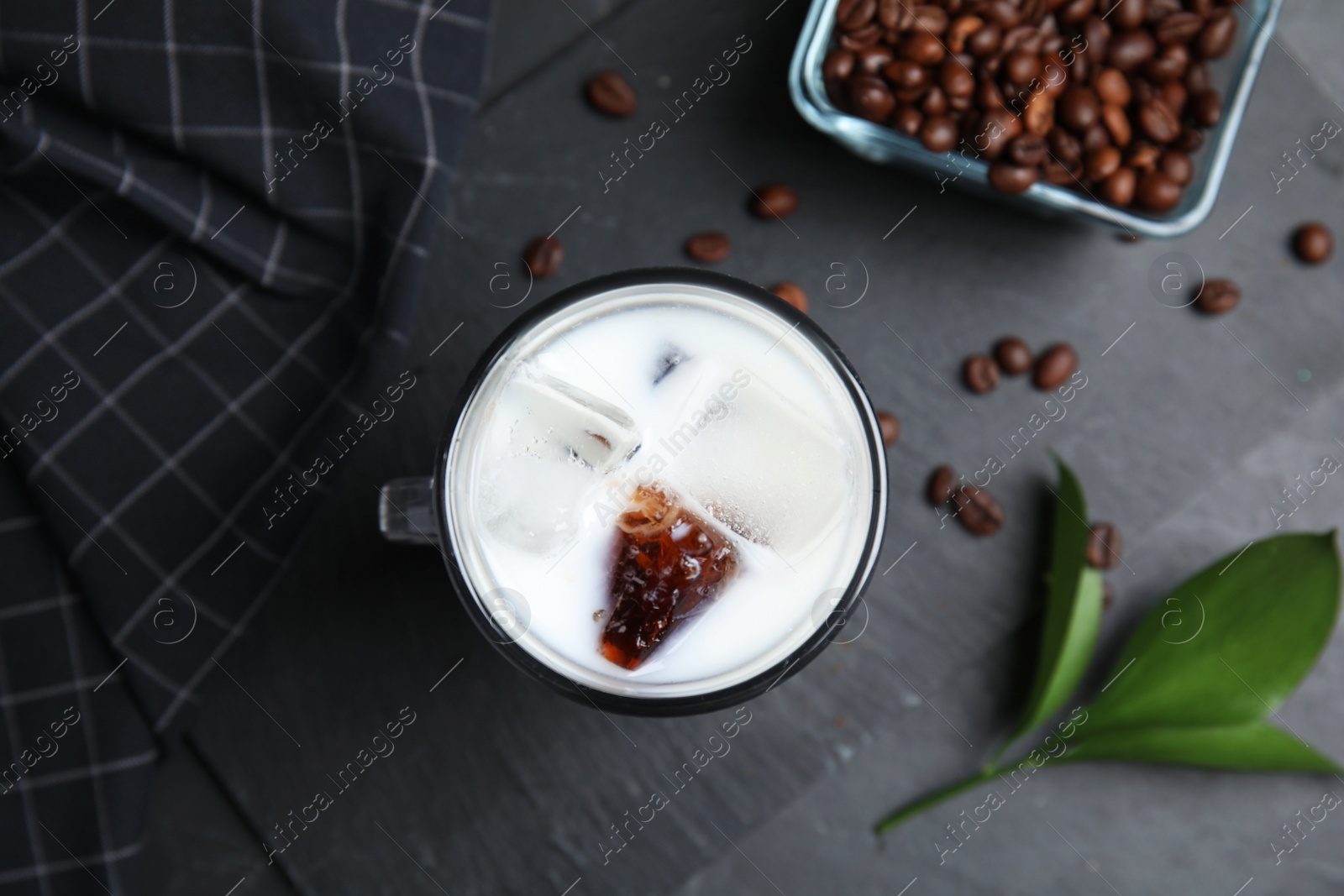 Photo of Glass cup of milk with delicious grass jelly, green leaf and coffee beans on black table, flat lay