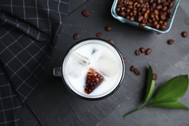 Photo of Glass cup of milk with delicious grass jelly, green leaf and coffee beans on black table, flat lay