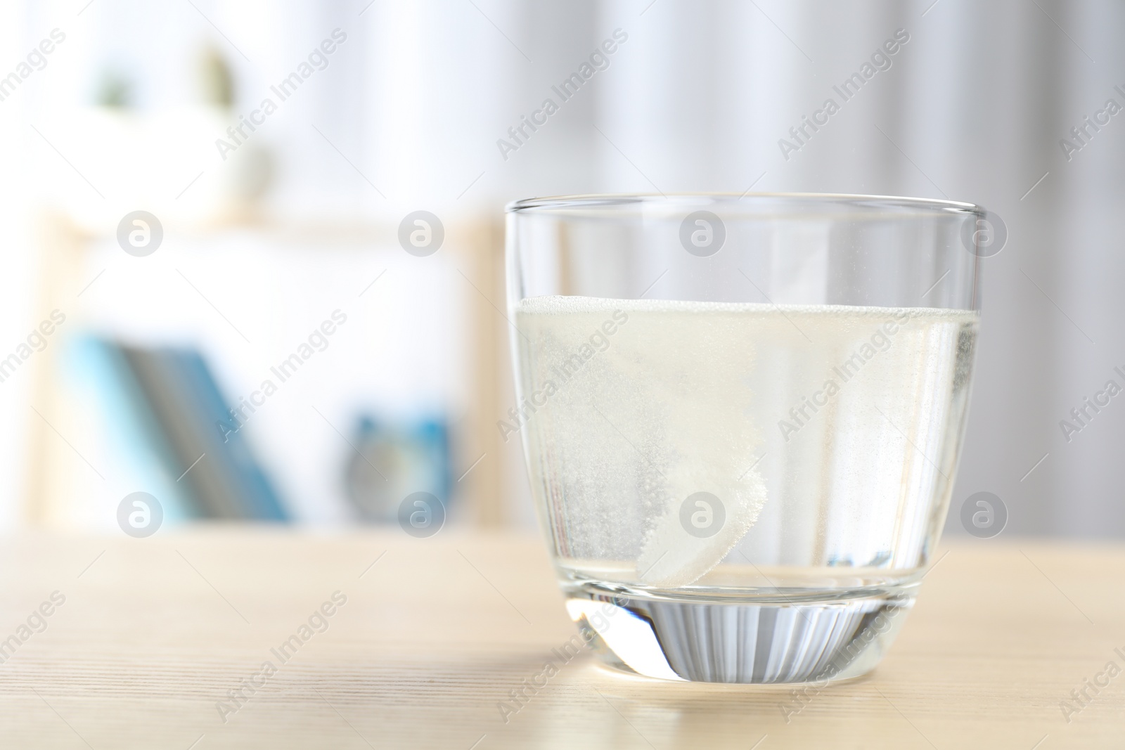 Photo of Glass of water with effervescent tablet on wooden table indoors, space for text