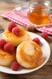 Delicious cottage cheese pancakes with raspberries on wooden table, closeup