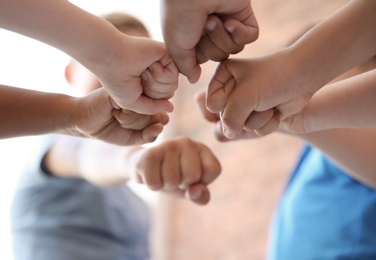 Photo of Little children putting their hands together on blurred background. Unity concept