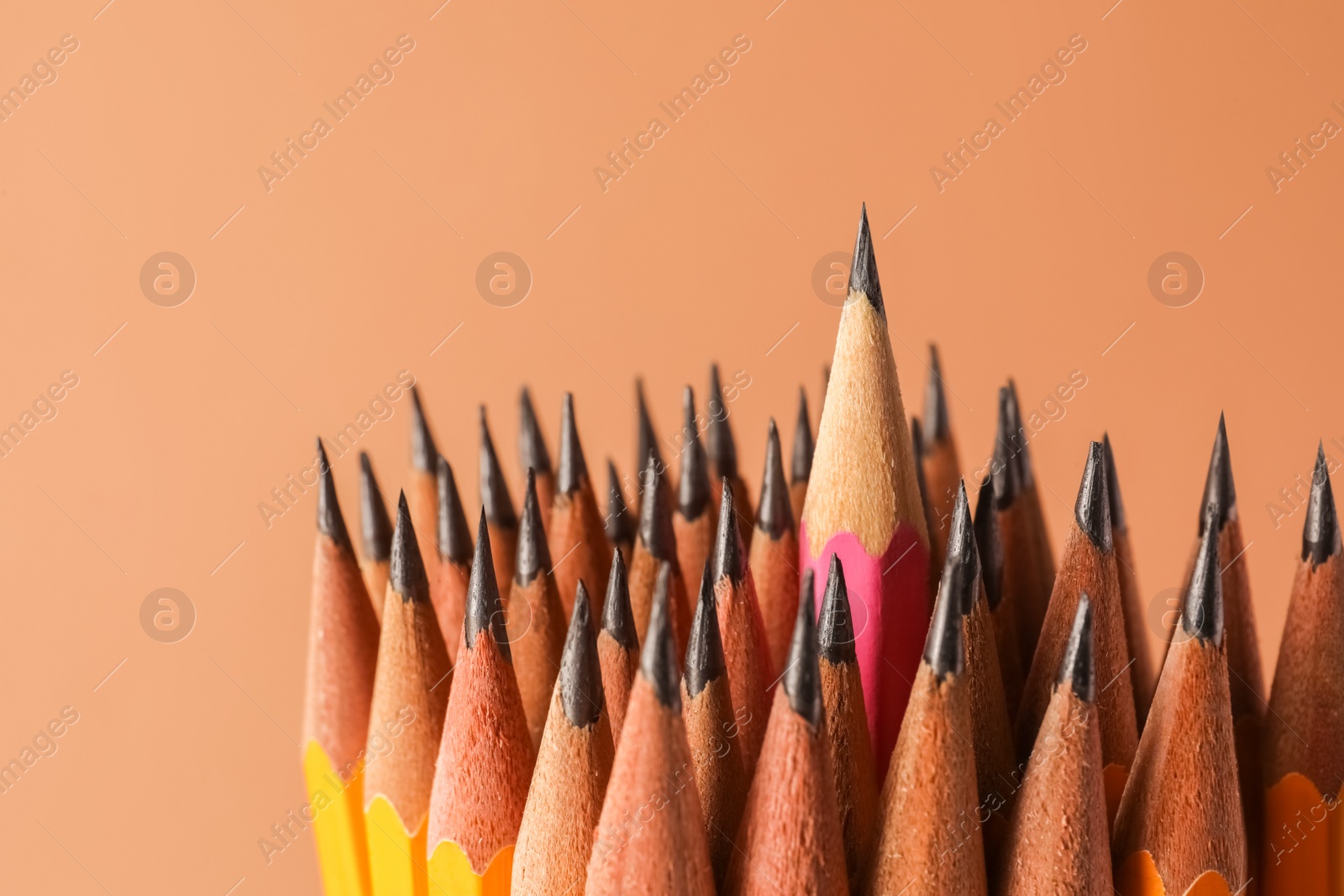 Photo of Many sharp graphite pencils on brown background, closeup. Space for text