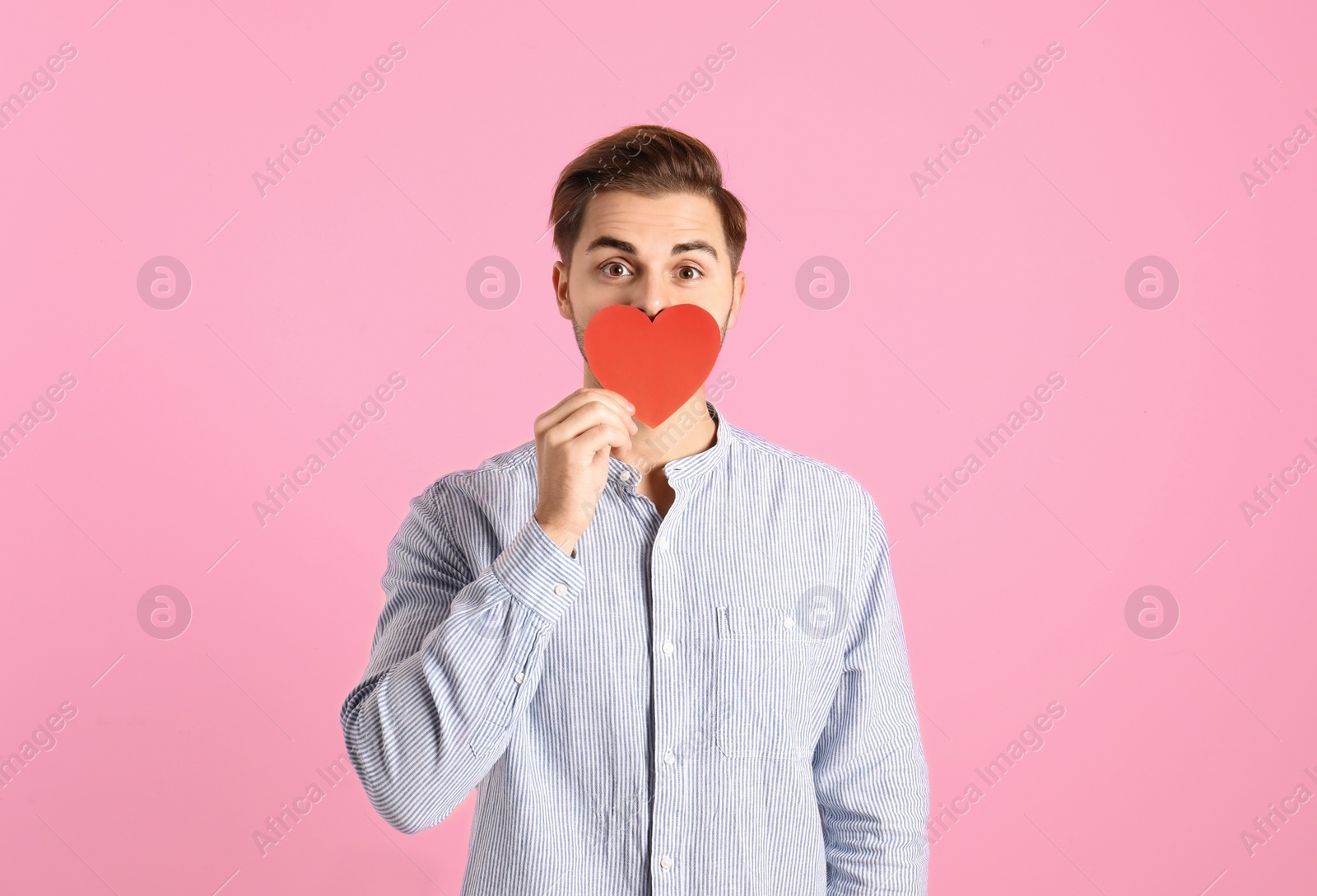 Photo of Portrait of young man with paper heart on color background