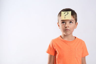 Emotional little boy with question mark on white background