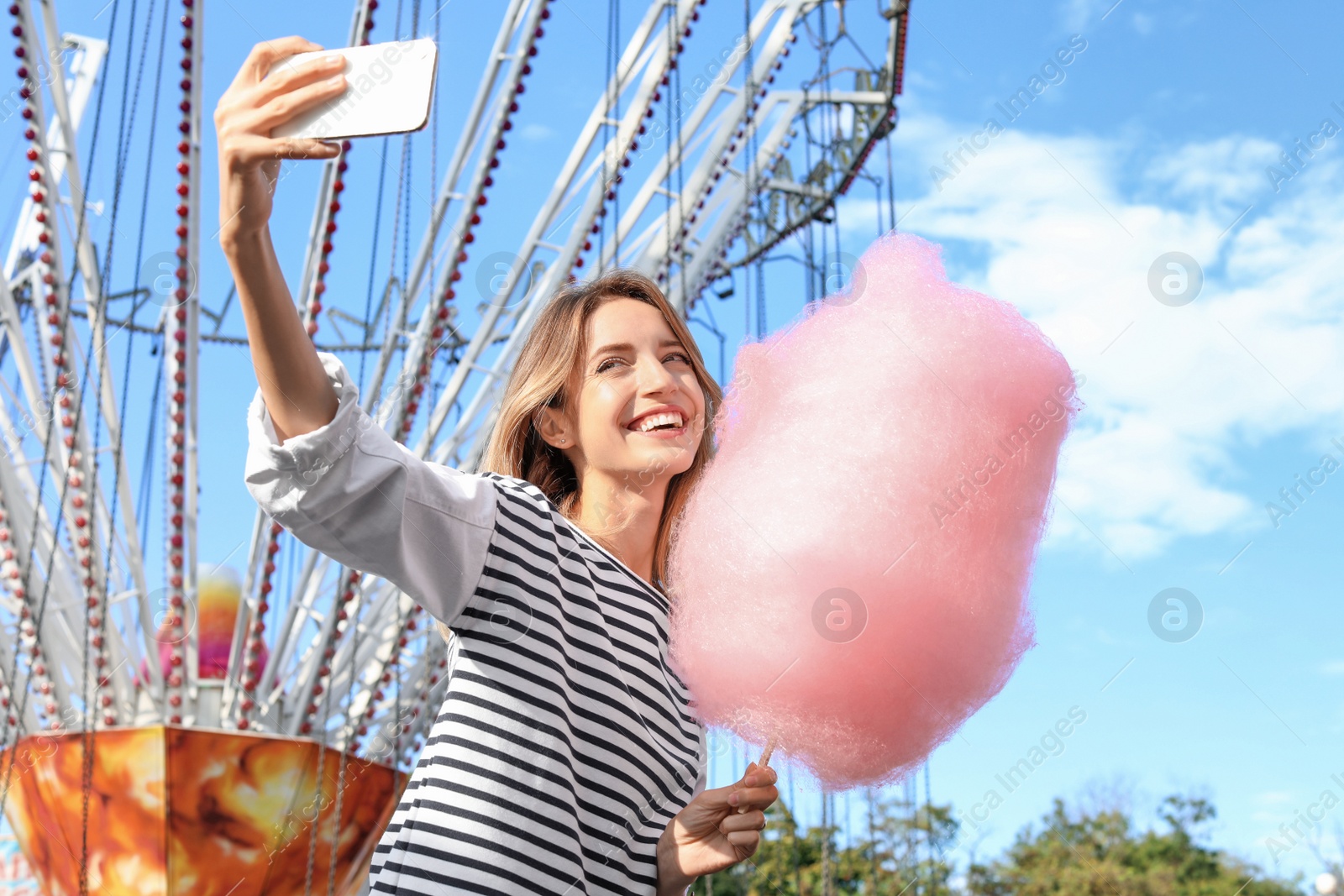 Photo of Attractive woman taking selfie with cotton candy in amusement park