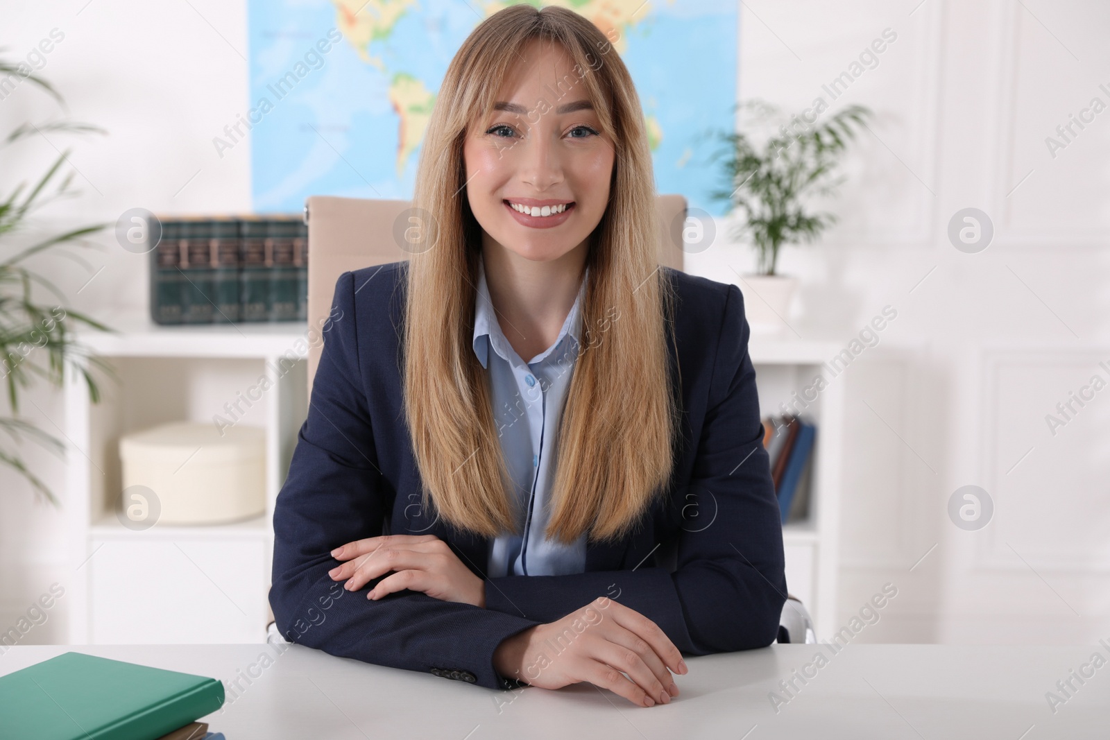 Photo of Happy manager with notebook sitting at desk in travel agency