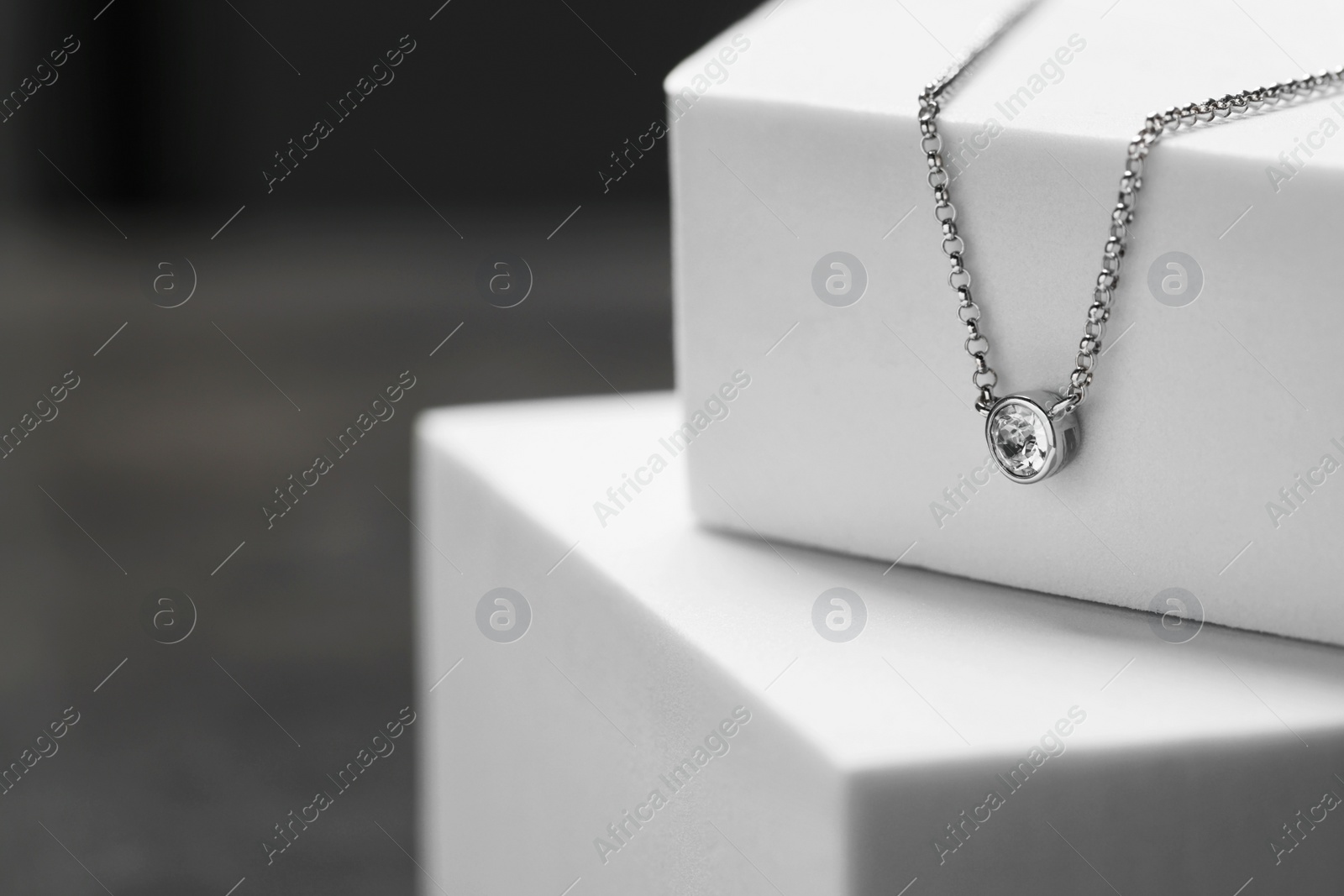 Photo of Beautiful necklace with gemstone on white podiums, space for text. Luxury jewelry