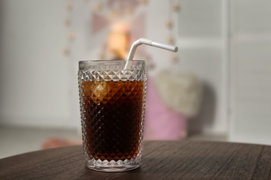 Photo of Glass of cold cola on table against blurred background