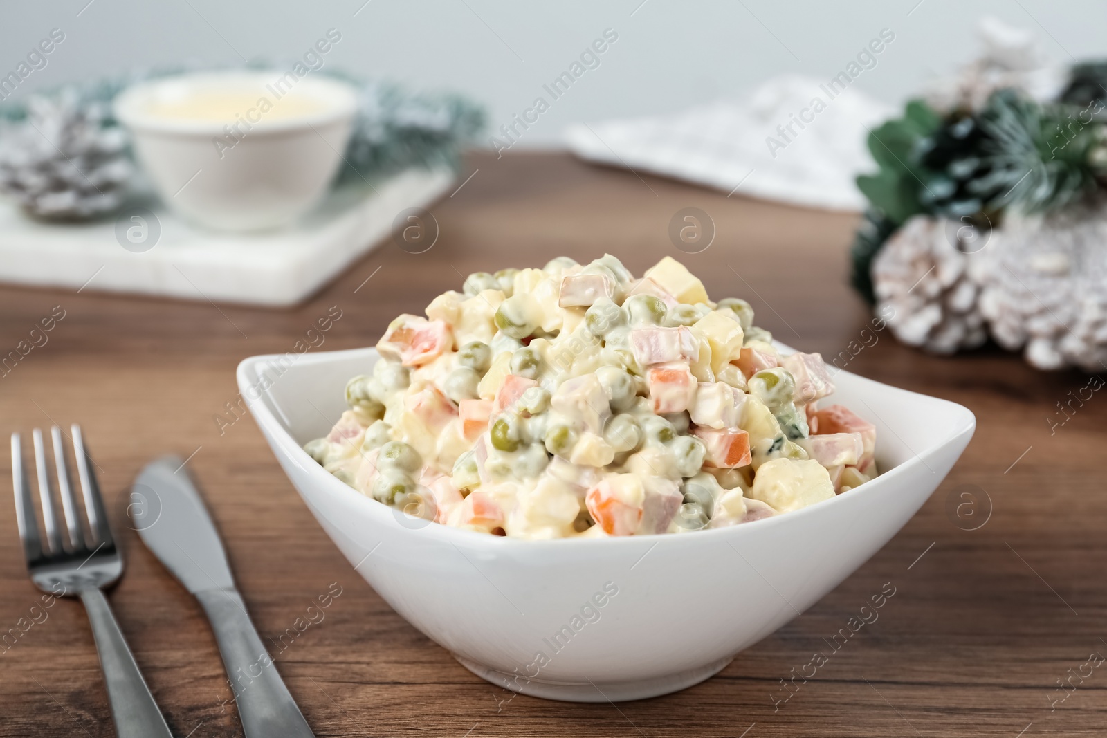 Photo of Traditional russian salad Olivier served on wooden table